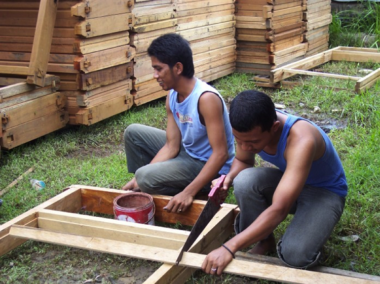 Indonesian students with wood and saw working on a project.