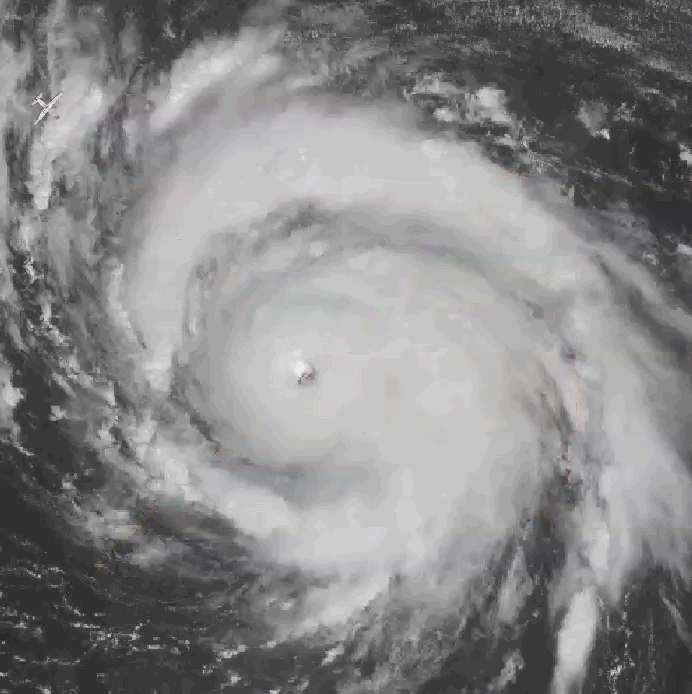 Satellite view of a hurricane with a clear eye and spiral cloud bands, and an aircraft near the edge.